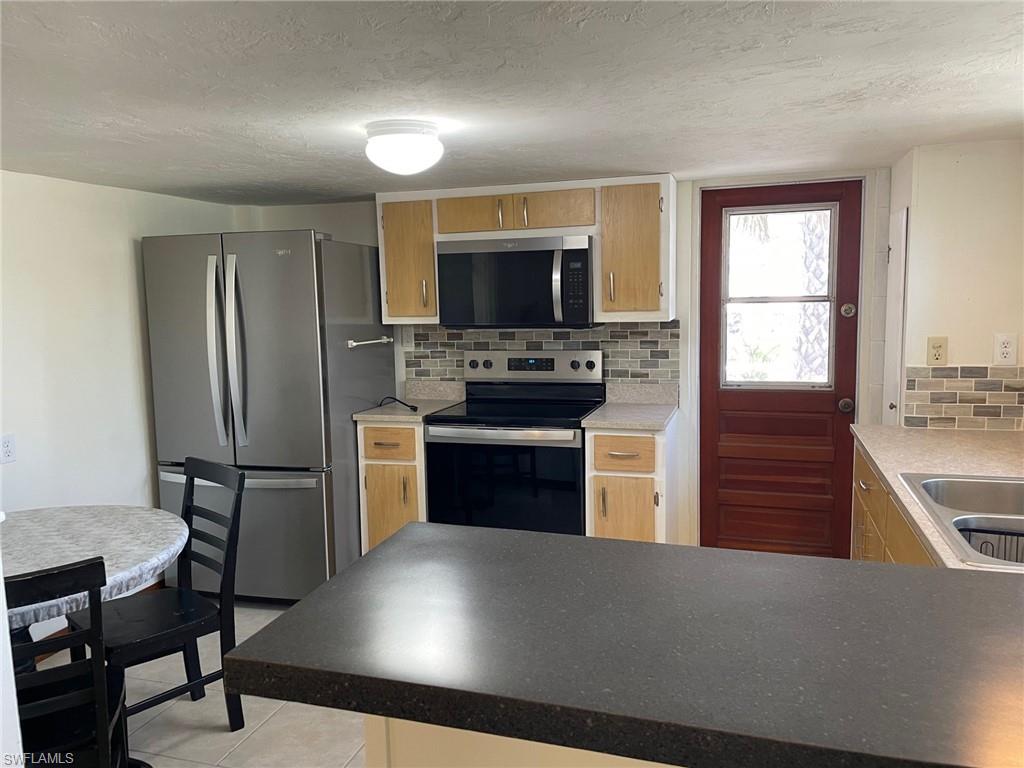 Kitchen with backsplash, Newappliances with stainless steel finishes, a textured ceiling, and a sink