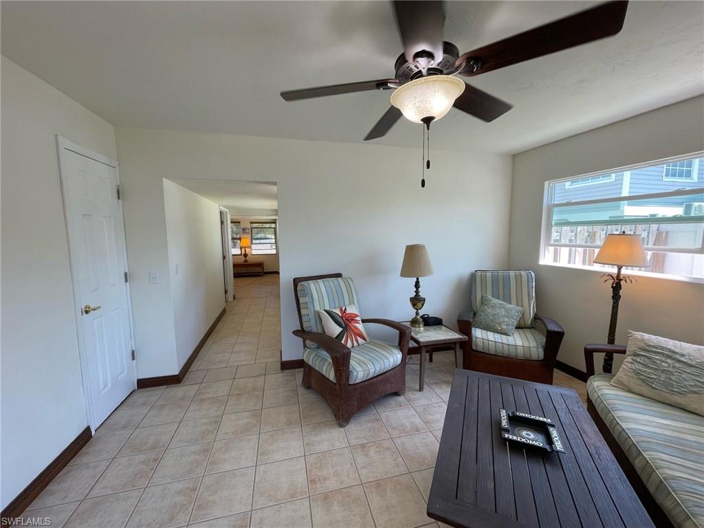 Living area featuring light tile patterned floors, baseboards, and ceiling fan