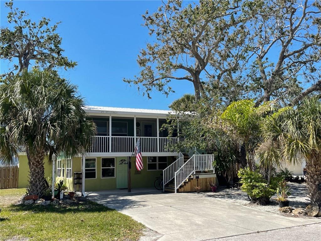 View of front of home with stairway, fence, a screened Lanai