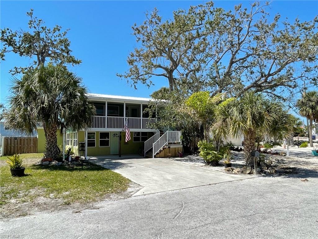 View of front of property featuring concrete driveway, fence, a screened Lanai and shady oak trees