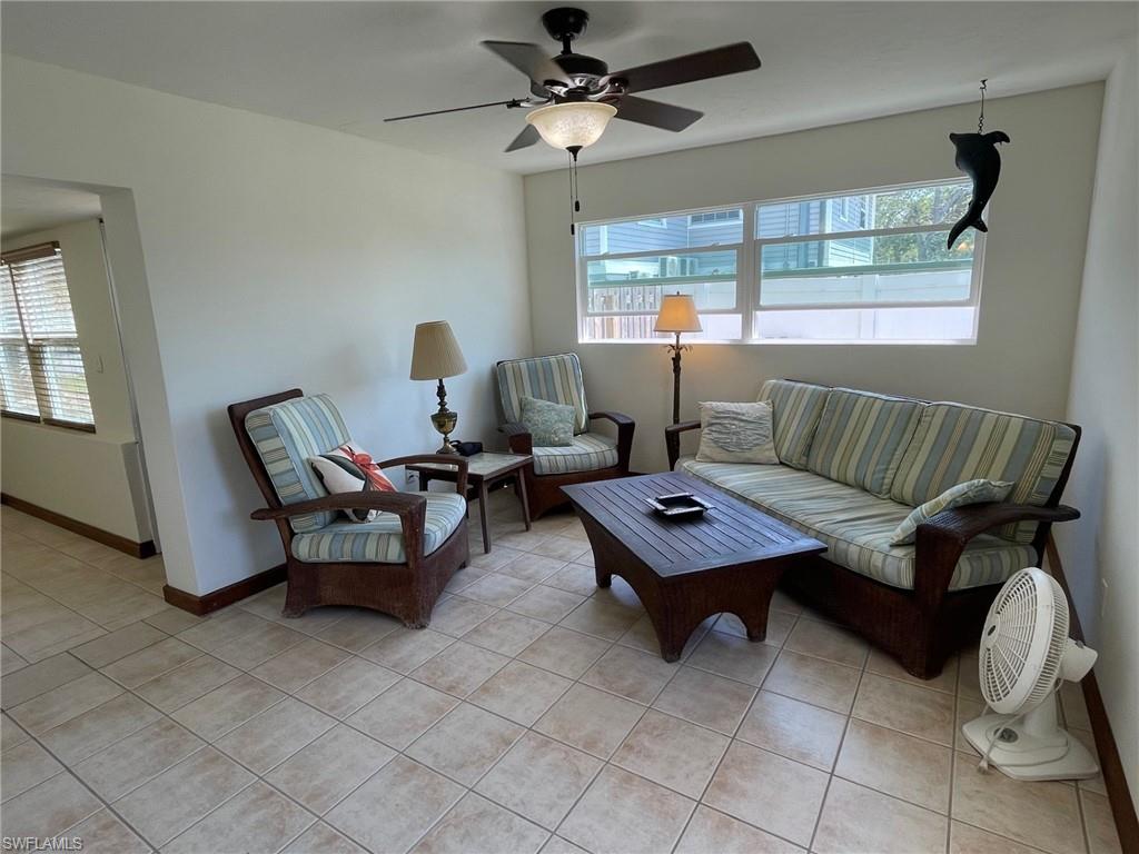 Living area with light tile patterned flooring, a healthy amount of sunlight, baseboards, and ceiling fan