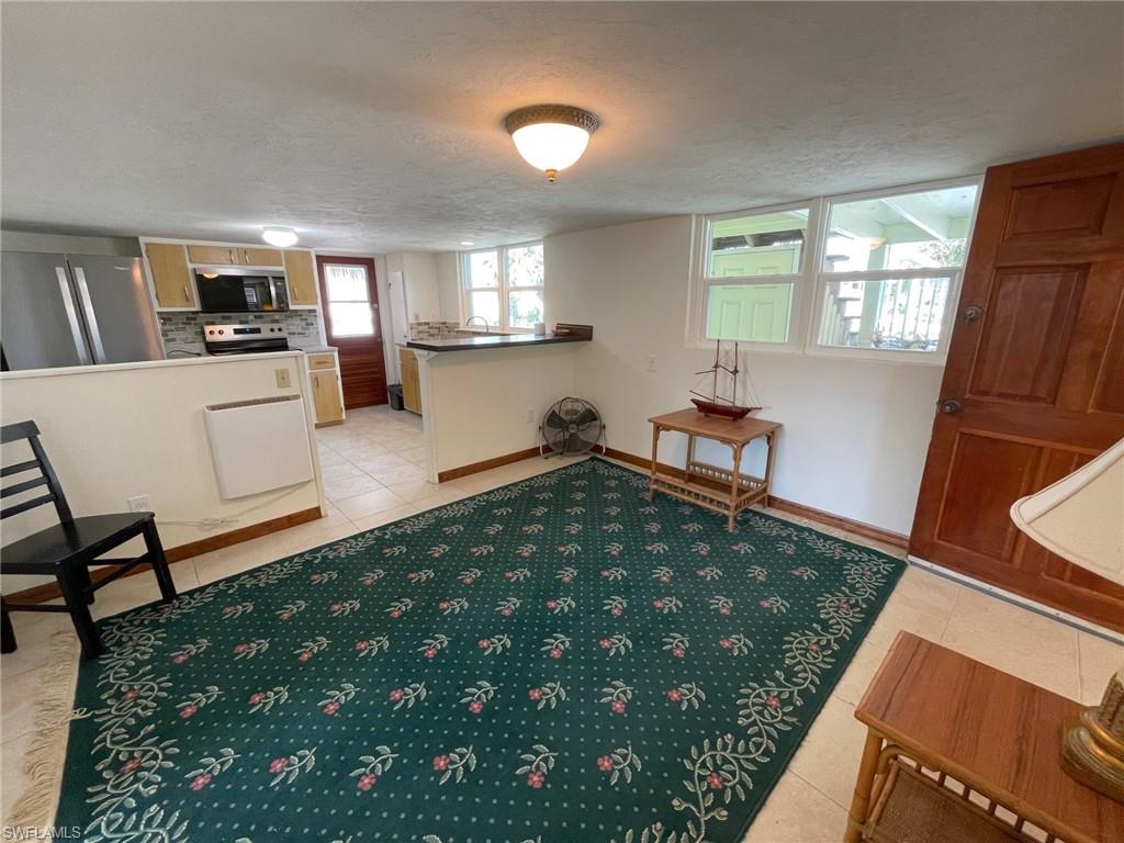 Sitting room featuring light tile patterned floors, a textured ceiling, and baseboards