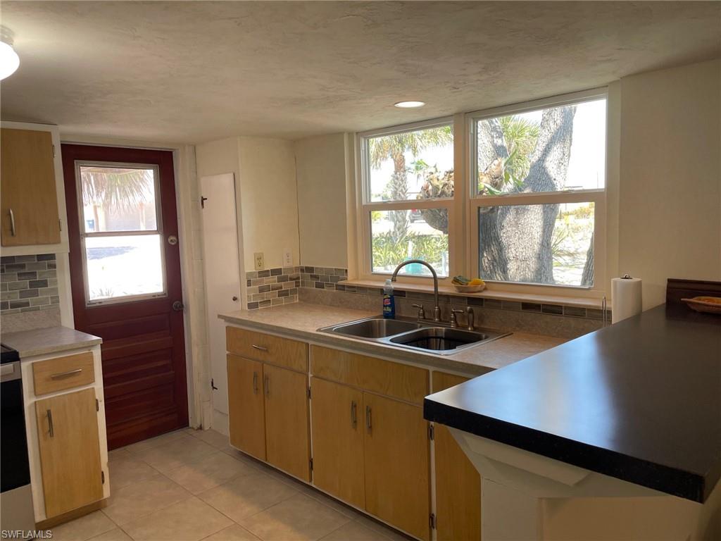 Kitchen featuring a sink, decorative backsplash, a textured ceiling, and light tile patterned floors