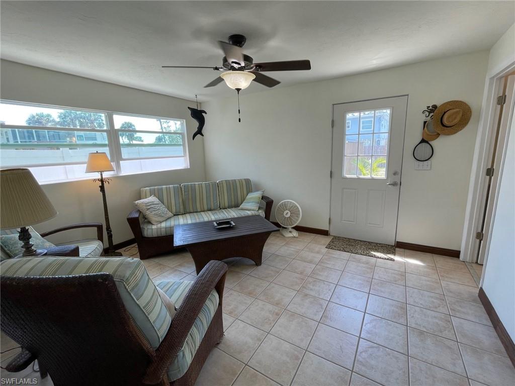 Living area with light tile patterned floors, plenty of natural light, baseboards, and a ceiling fan