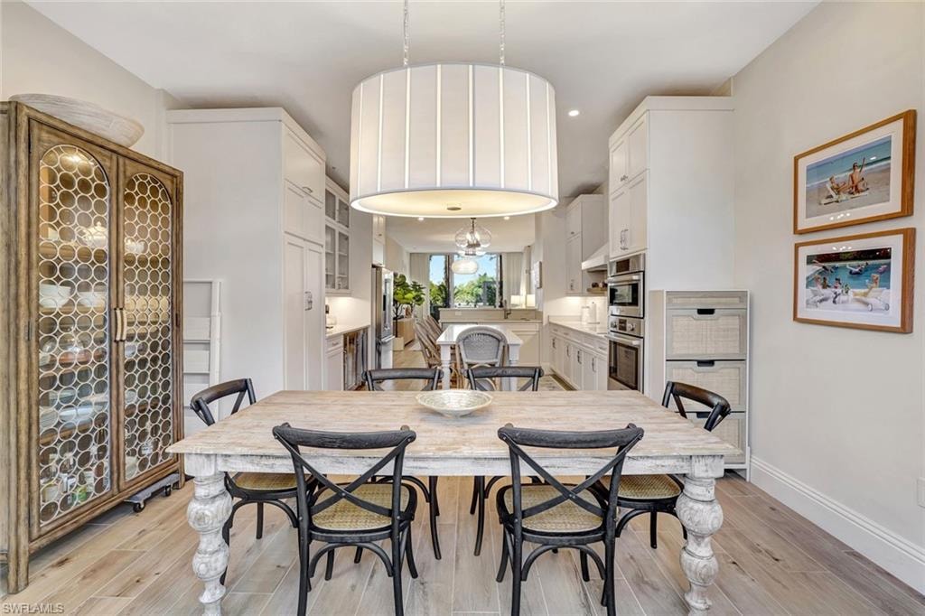Expansive dining room with light wood-style flooring, beverage cooler, and a chandelier