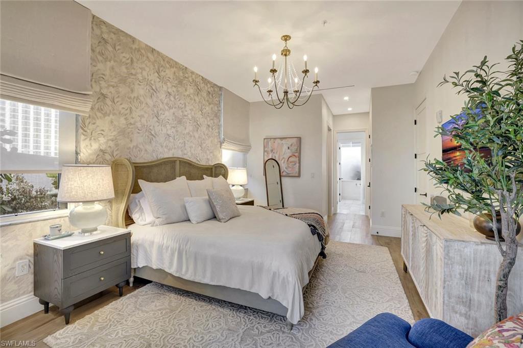 Master bedroom with suspended lighting, light wood-style flooring, wallpapered walls, and multiple windows