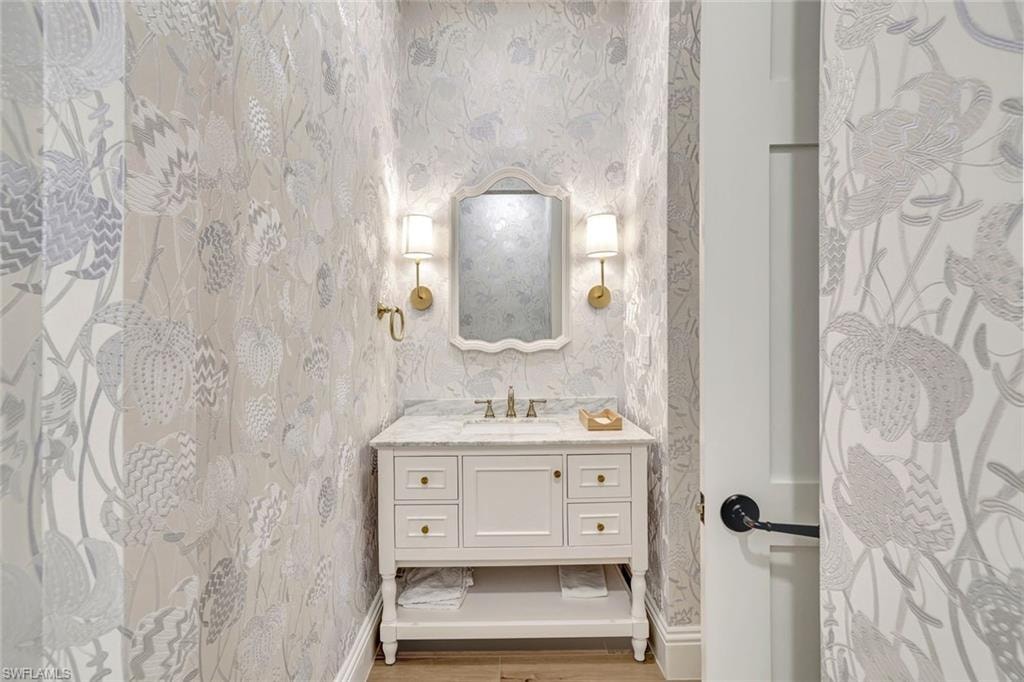 Half bathroom featuring vanity and wallpapered walls