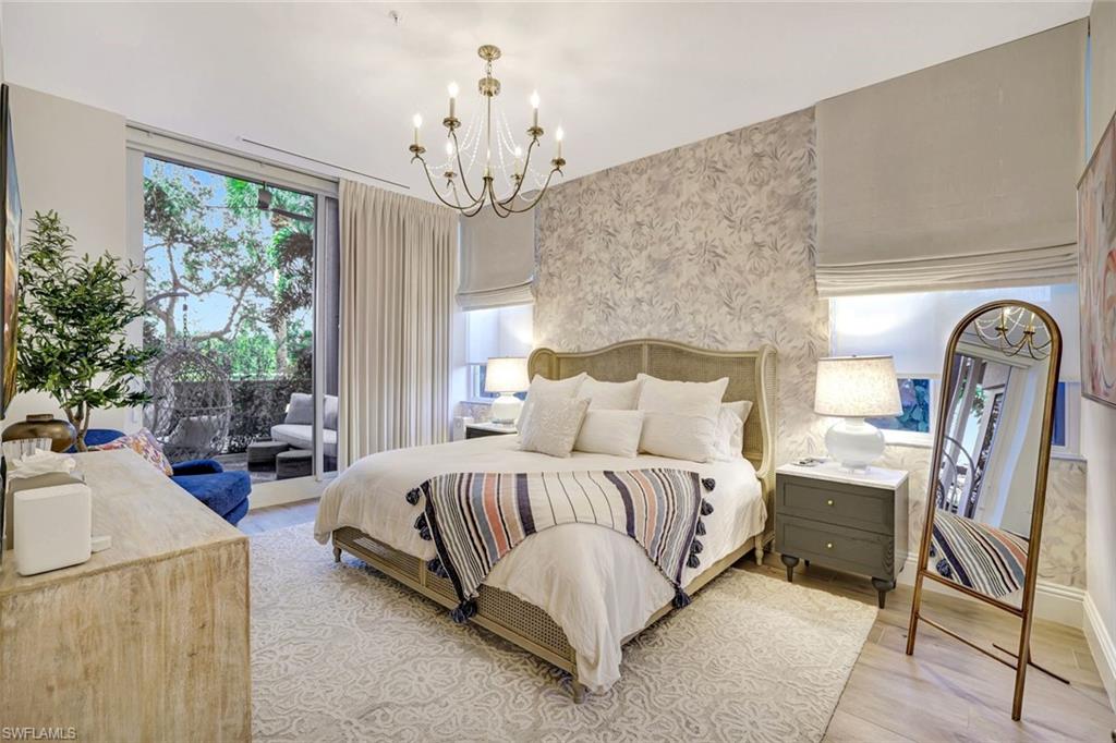Master bedroom featuring a king bed, tastefully wallpapered walls, a chandelier, light wood-style floors, and access to exterior