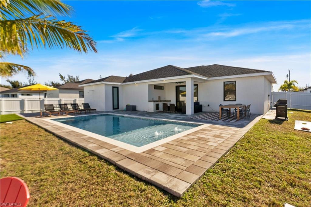 Back of house featuring a fenced backyard, stucco siding, a patio area, roof with shingles, and a bar