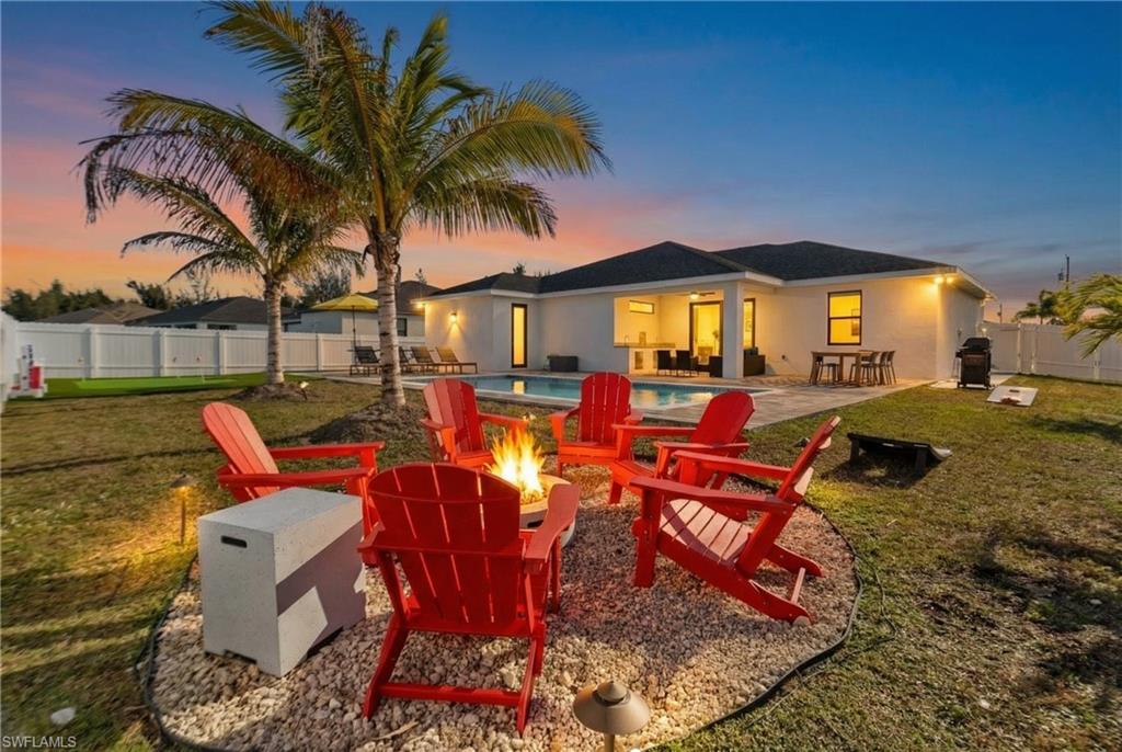 Rear view of house featuring a fenced backyard, an outdoor fire pit, a patio area, and stucco siding