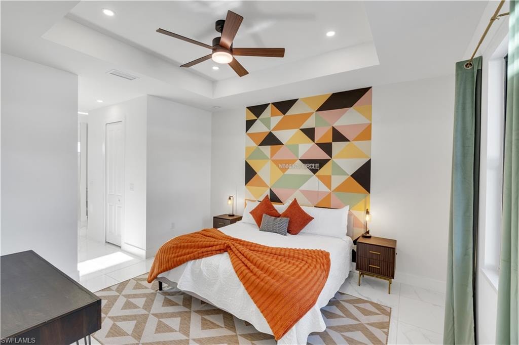 Bedroom featuring an accent wall, a raised ceiling, a ceiling fan, and recessed lighting