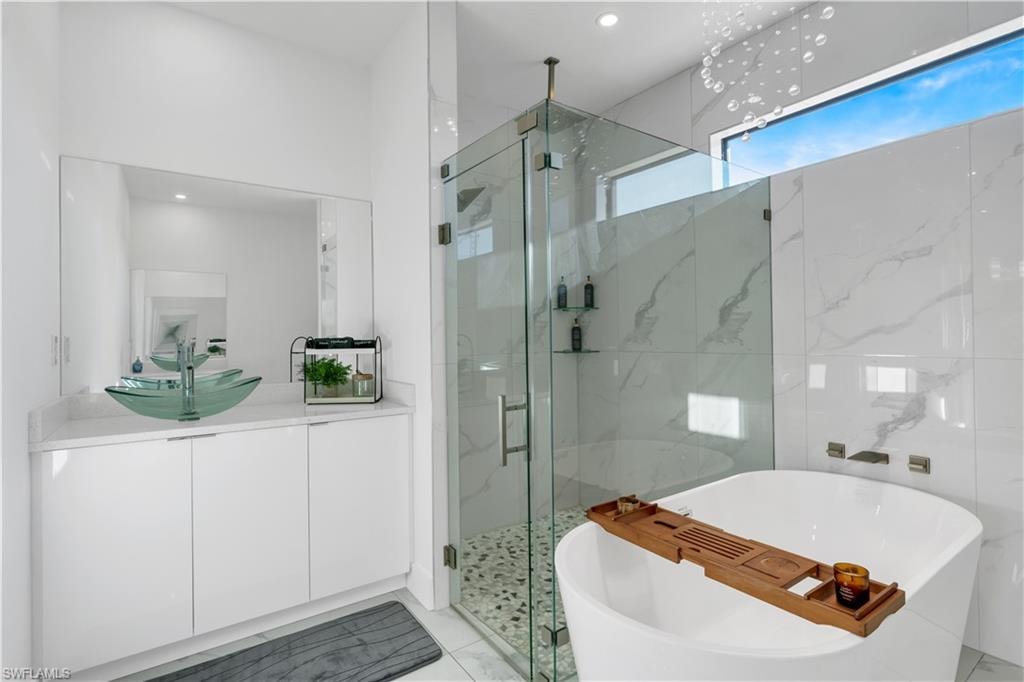 Bathroom featuring a marble finish shower, a freestanding bath, vanity, and recessed lighting