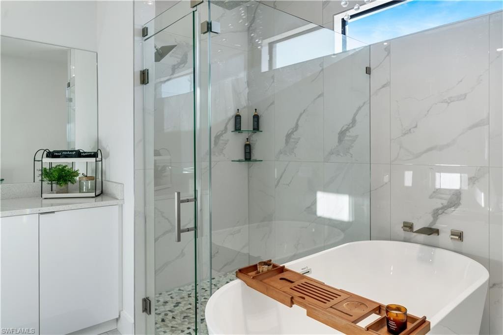 Full bathroom with a soaking tub and a marble finish shower