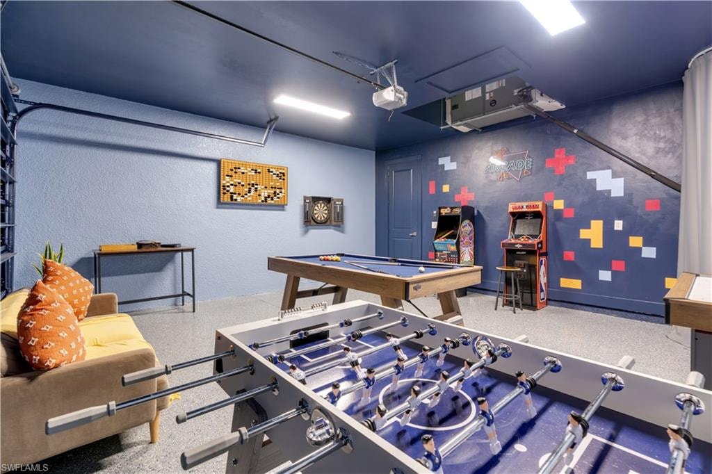 Game room with billiards table, a garage, and a textured wall
