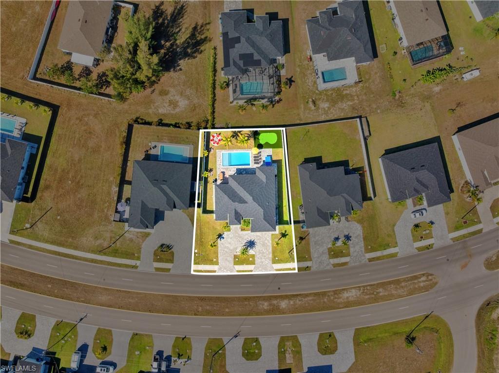 Aerial perspective of suburban area featuring property parcel outlined and a pool area