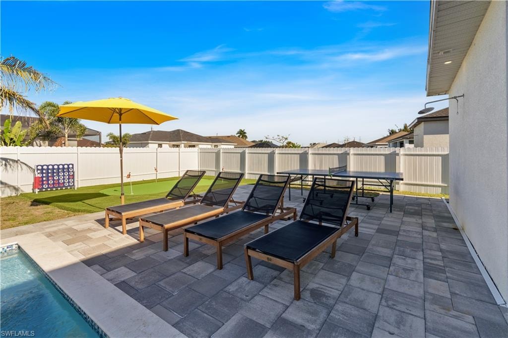 Fenced backyard with a patio, a putting green, outdoor dining space, and an outdoor pool