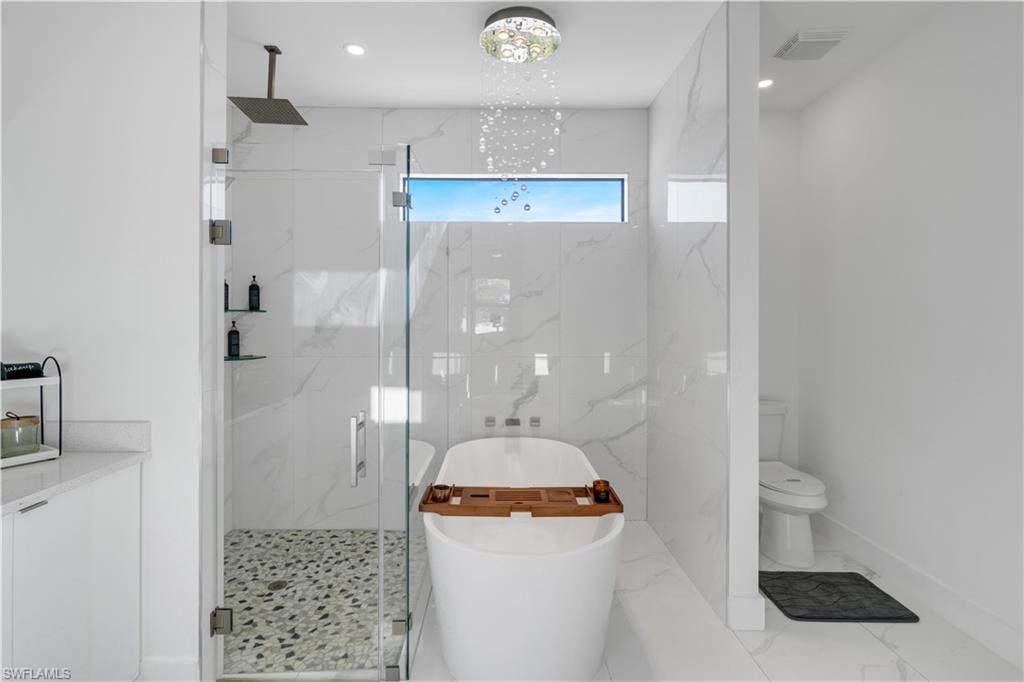 Bathroom with a soaking tub, a marble finish shower, recessed lighting, and marble finish flooring