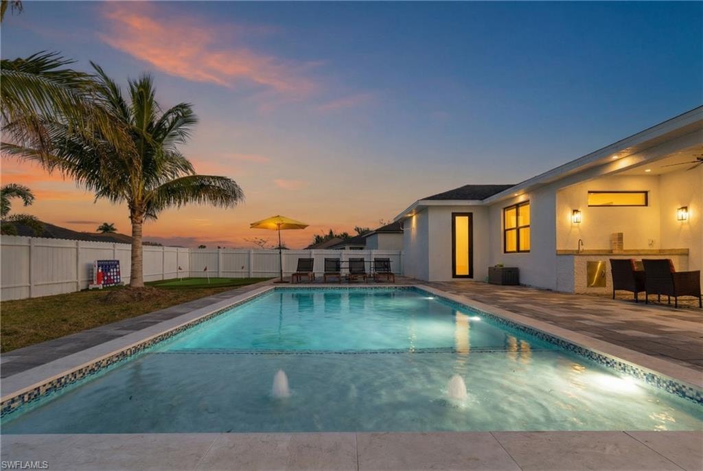 View of pool with a patio area, a fenced backyard, and an outdoor bar