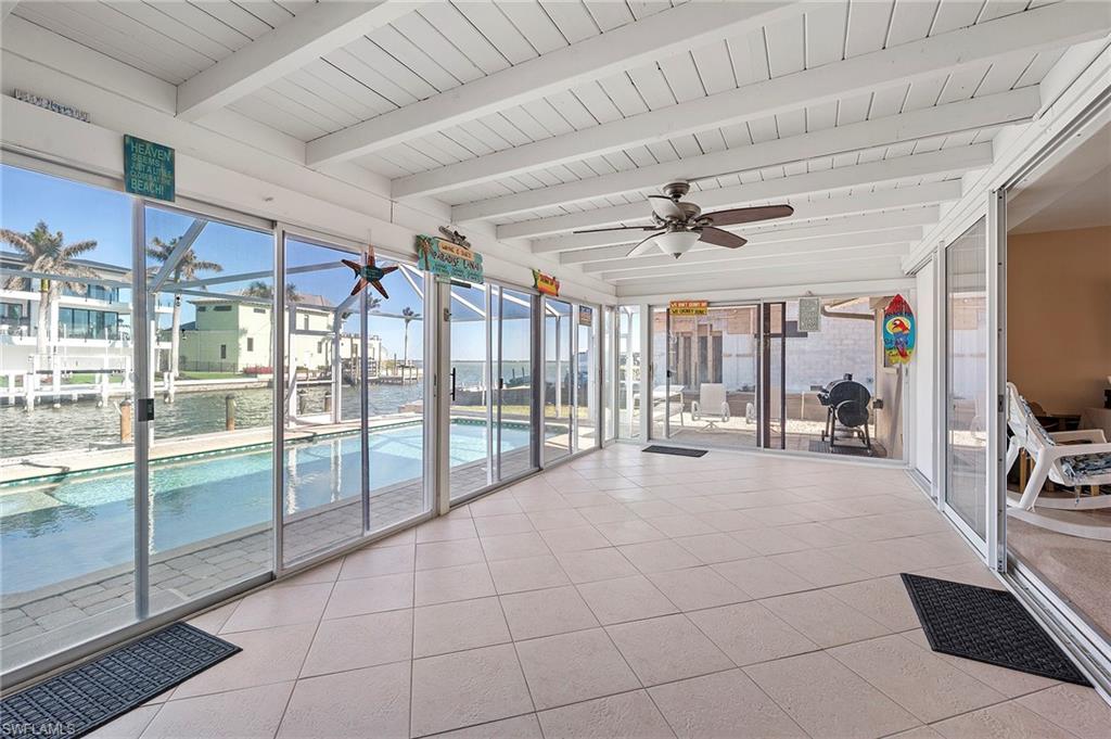 Unfurnished sunroom featuring beamed ceiling, a water view, a healthy amount of sunlight, and ceiling fan