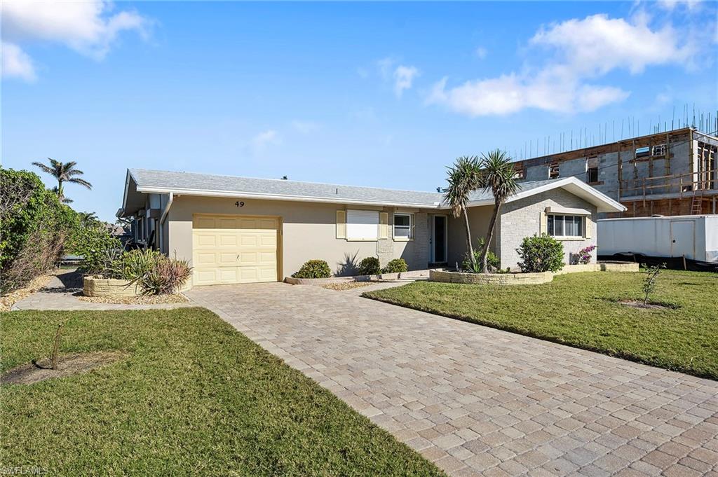 Single story home featuring a garage and a front lawn