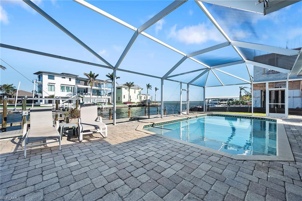 View of pool featuring a patio, a water view, and glass enclosure