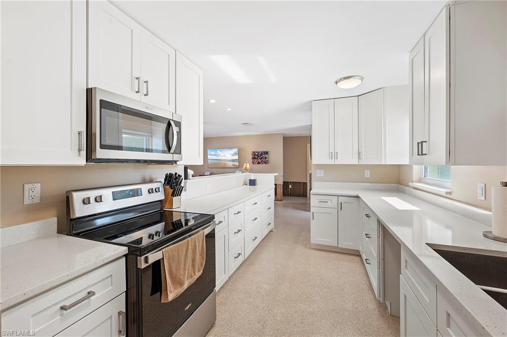 Kitchen featuring white cabinetry, stainless steel appliances, and light stone countertops