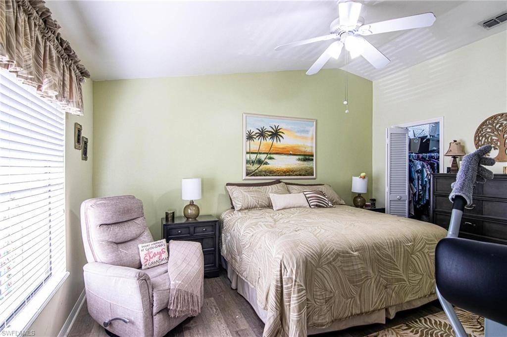 Bedroom featuring dark hardwood / wood-style flooring, vaulted ceiling, ceiling fan, a spacious closet, and a closet