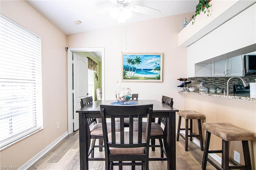 Dining space with ceiling fan, sink, vaulted ceiling, and light hardwood / wood-style flooring