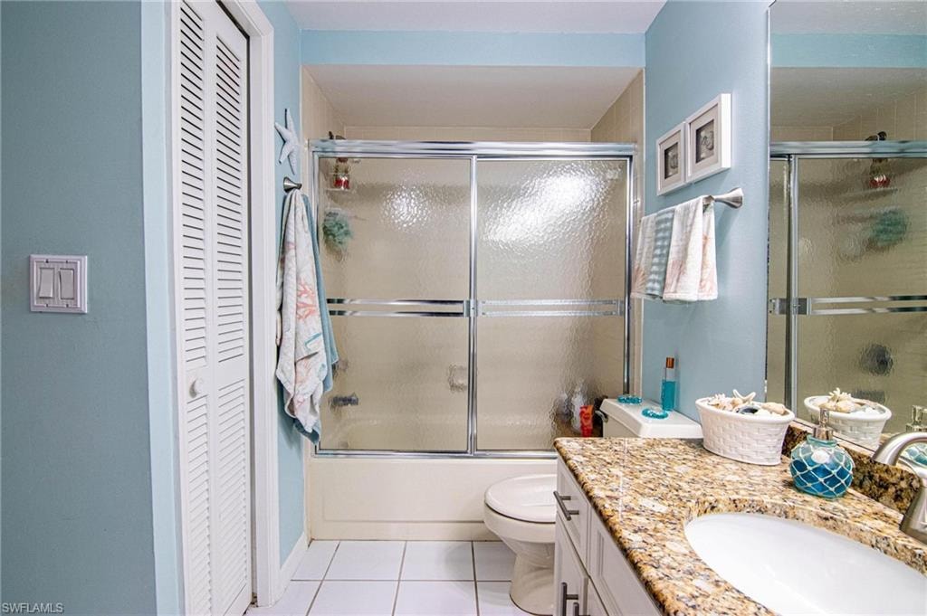 Full bathroom featuring tile patterned flooring, vanity, bath / shower combo with glass door, and toilet