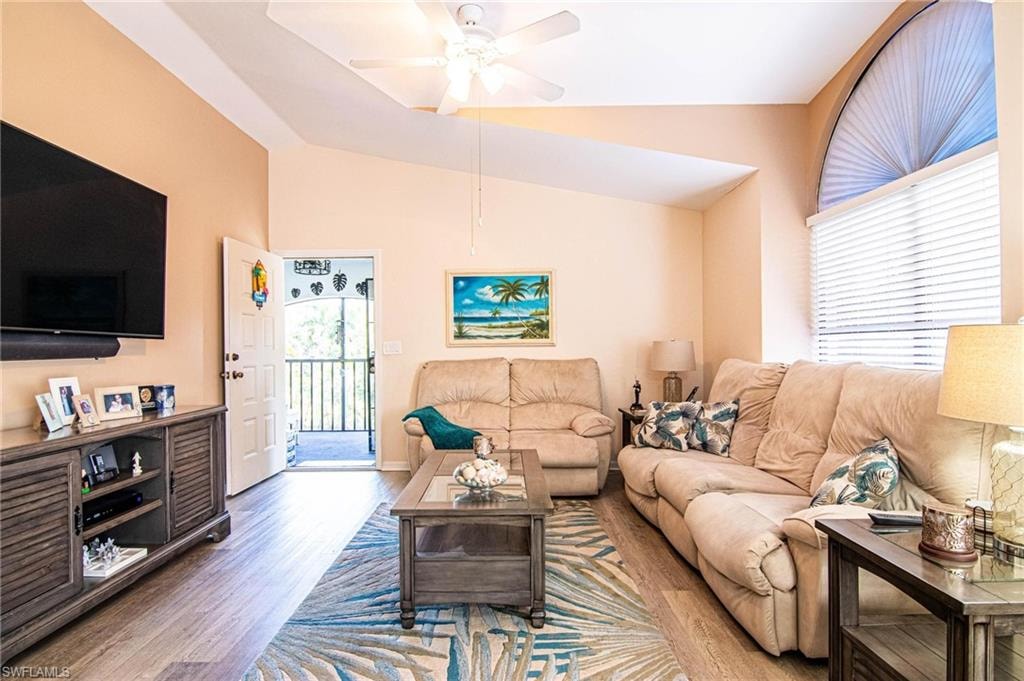 Living room with hardwood / wood-style floors, vaulted ceiling, and ceiling fan