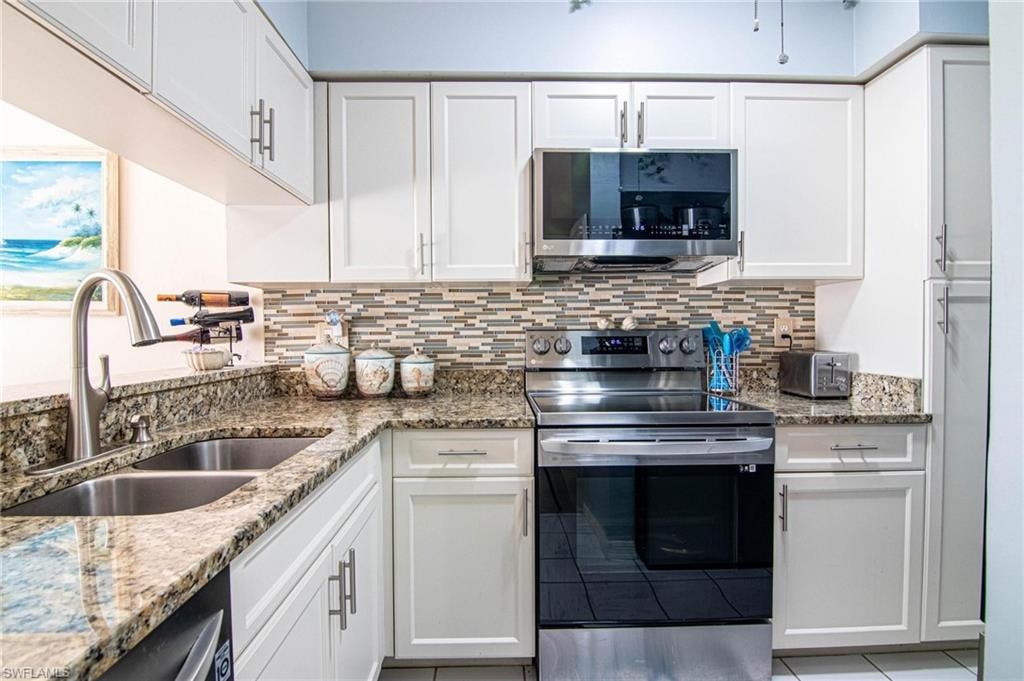 Kitchen featuring light stone countertops, sink, white cabinetry, and stainless steel appliances