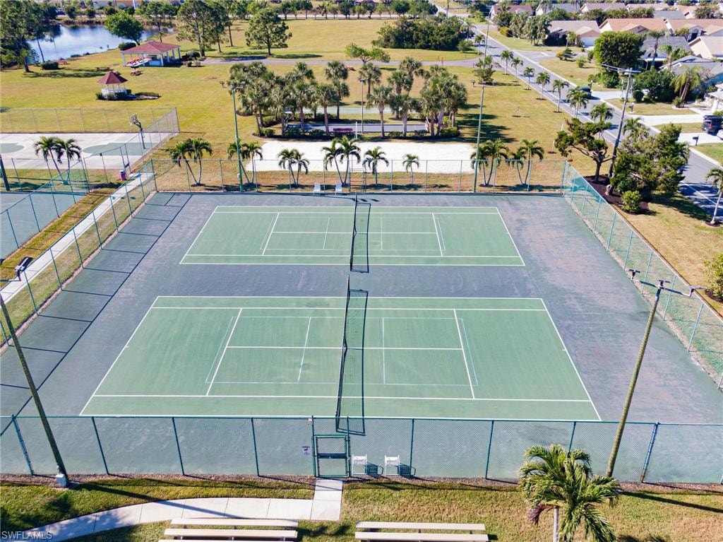 View of tennis court with basketball court and a water view