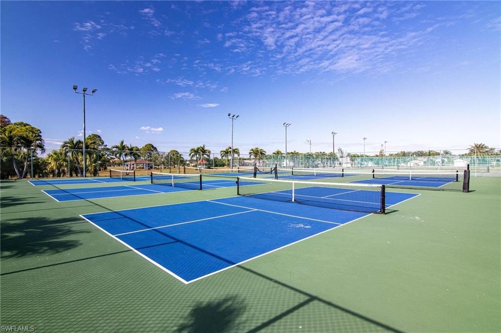 View of tennis court featuring basketball hoop