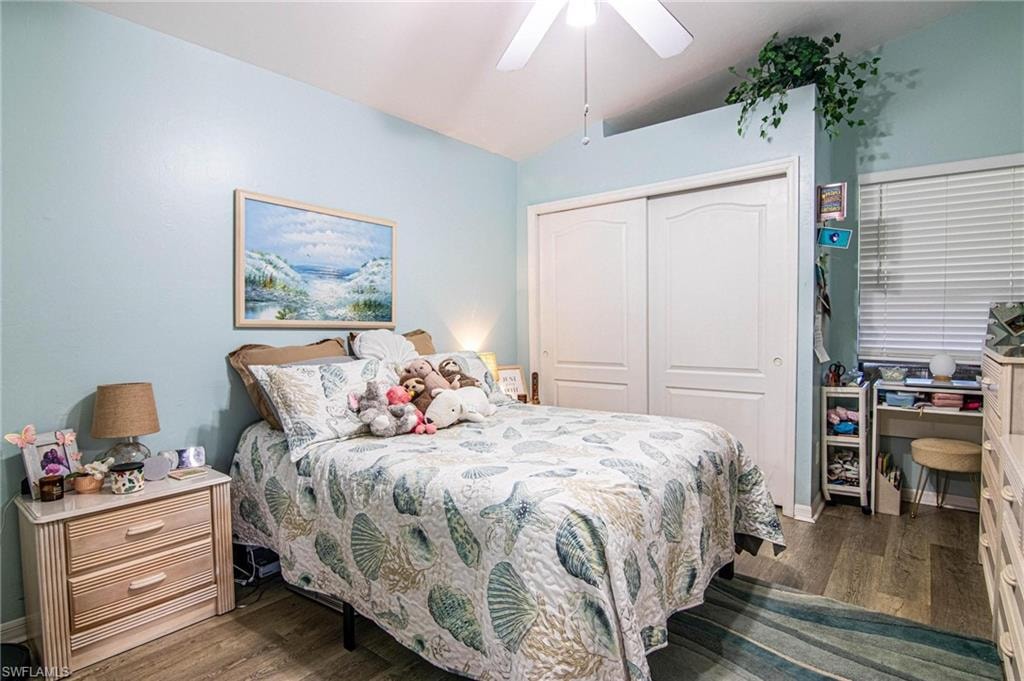 Bedroom featuring ceiling fan, dark hardwood / wood-style floors, lofted ceiling, and a closet
