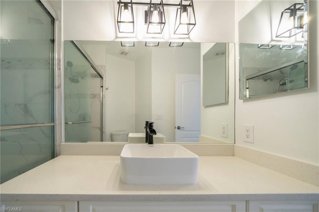 Bathroom featuring a marble finish shower and vanity