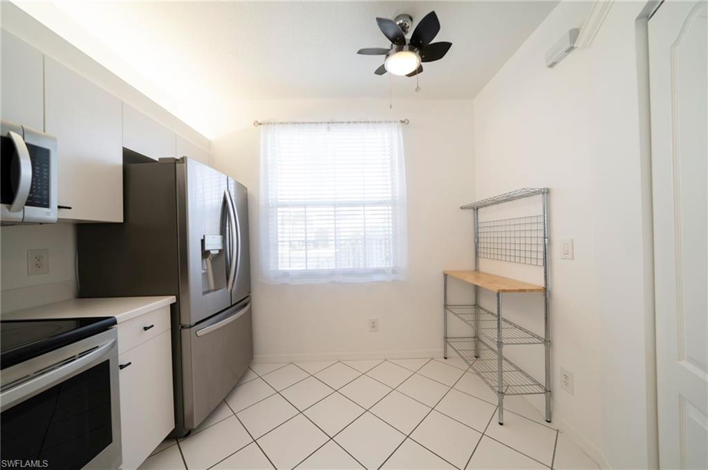 Kitchen with white cabinets, light countertops, stainless steel electric stove, ceiling fan, and light tile patterned flooring
