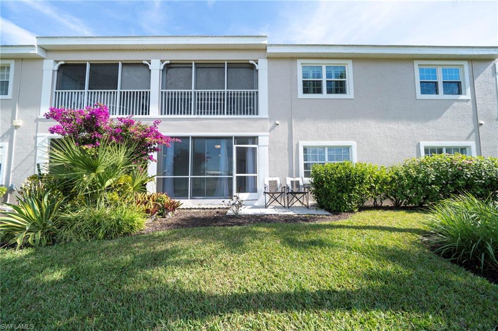 Back of house featuring a sunroom, stucco siding, a lawn, a balcony, and a patio