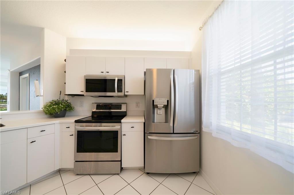 Kitchen with appliances with stainless steel finishes, white cabinets, light countertops, and light tile patterned flooring