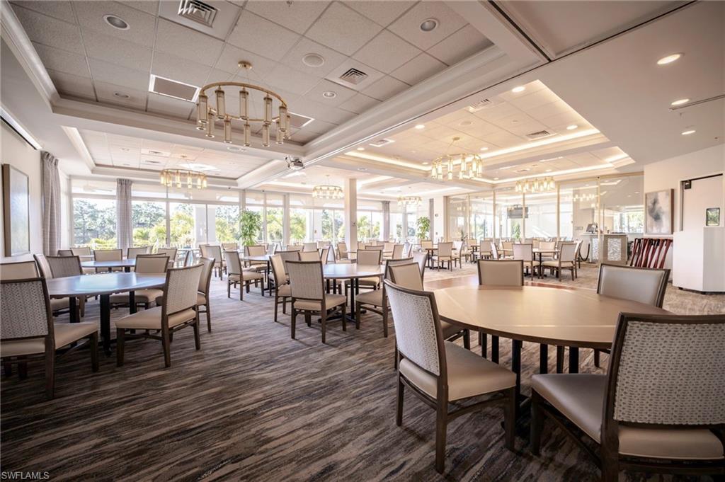Club house-Dining room featuring a tray ceiling, carpet floors, crown molding, hanging lights, and healthy amount of natural light