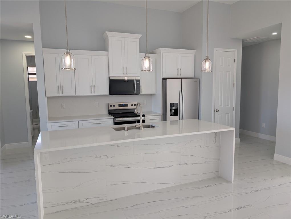 Kitchen featuring stainless steel appliances, recessed lighting, light stone countertops, an island with sink, and decorative light fixtures