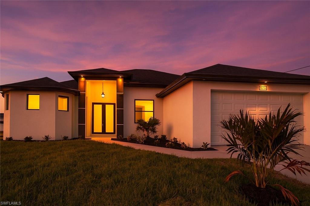 Coastal Modern home featuring a front yard, stucco siding, and a garage