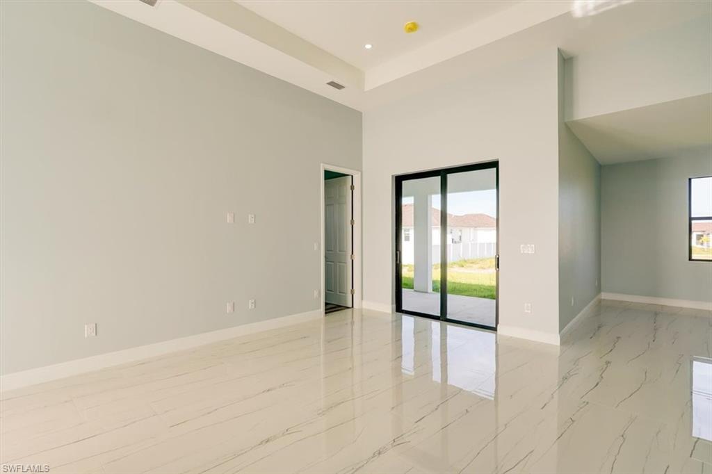 Spare room with a high ceiling, recessed lighting, and light marble finish flooring