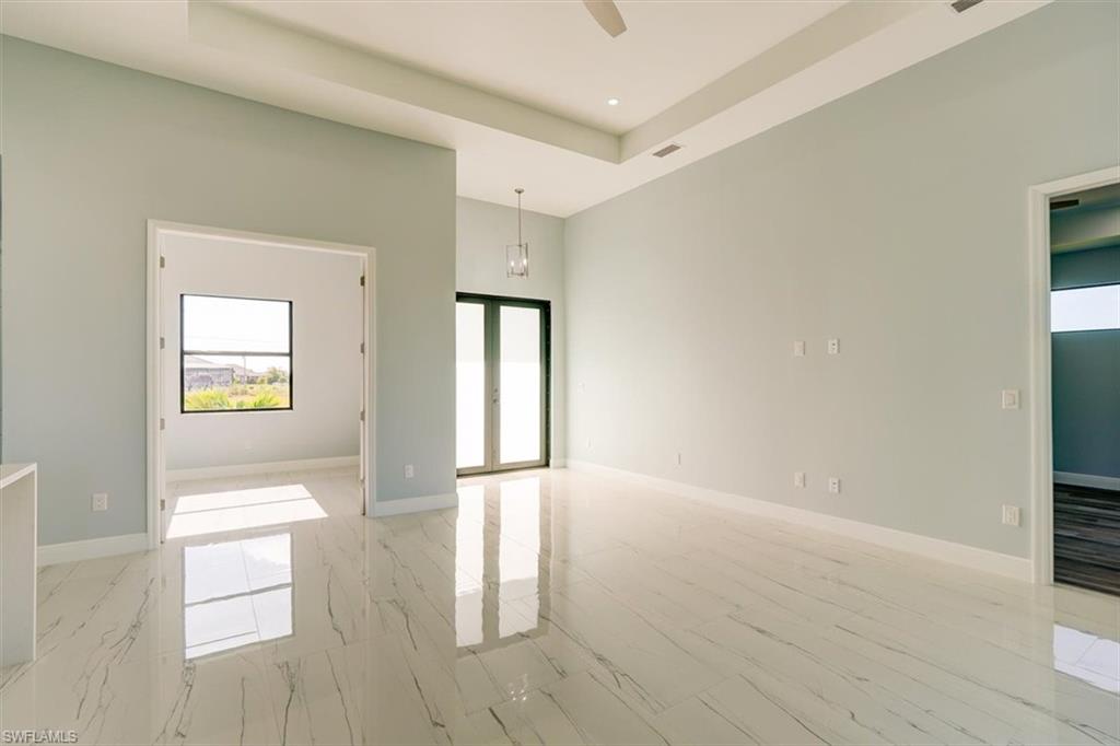 Empty room with a high ceiling, ceiling fan, and french doors