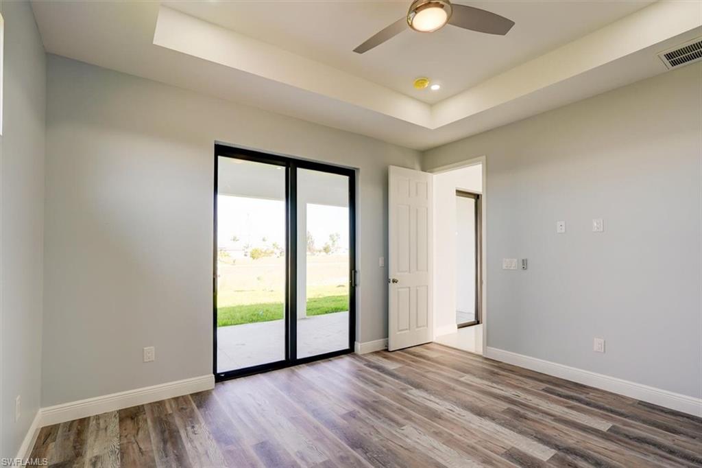 Empty room featuring a raised ceiling, wood finished floors, recessed lighting, and ceiling fan