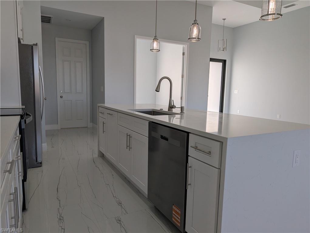 Kitchen featuring white cabinetry, appliances with stainless steel finishes, pendant lighting, and light stone countertops