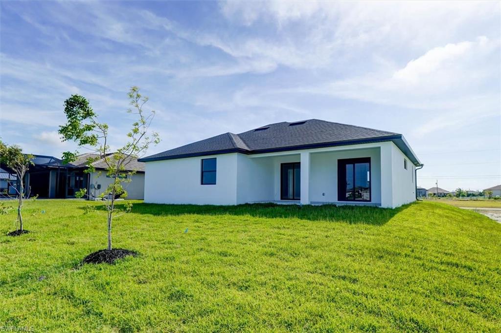 Back of property featuring stucco siding, a patio, and a lawn