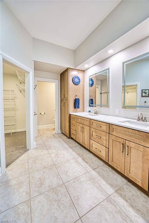 Bathroom featuring double vanity, a spacious closet, and light tile patterned floors