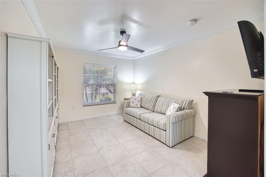 Living area with crown molding, light tile patterned floors, and a ceiling fan