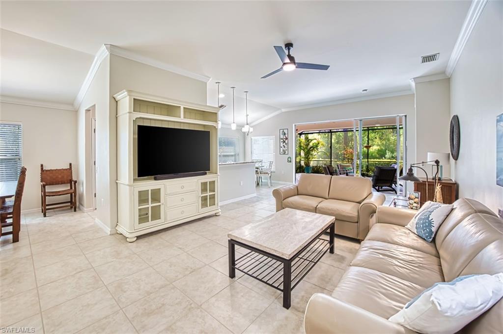 Living area featuring ornamental molding, lofted ceiling, a ceiling fan, and light tile patterned floors