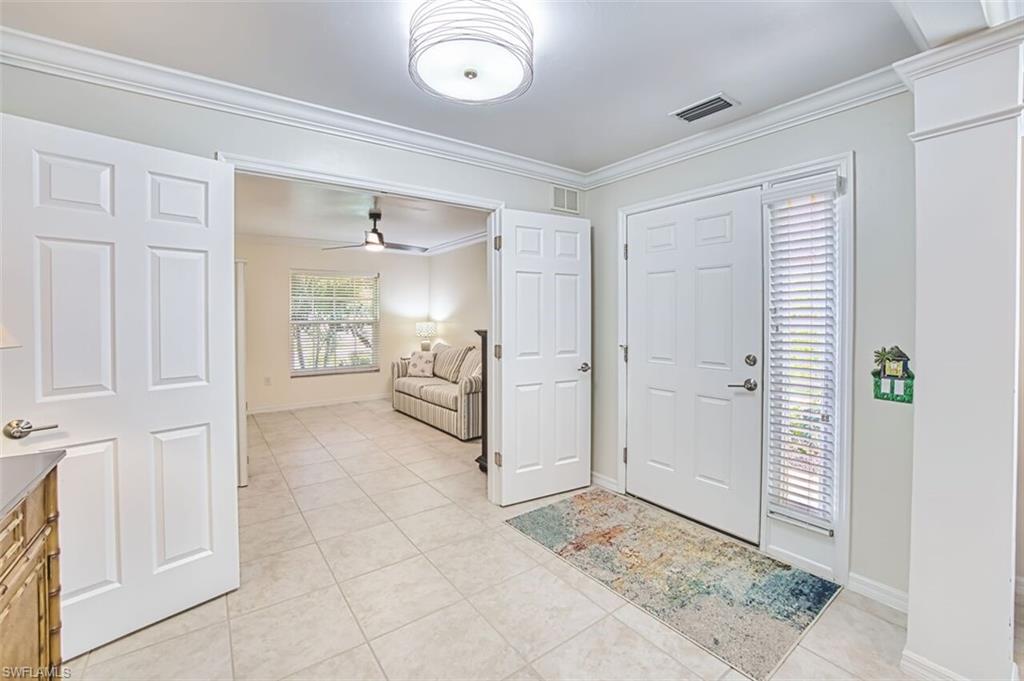 Entryway featuring ornamental molding, a ceiling fan, and light tile patterned floors